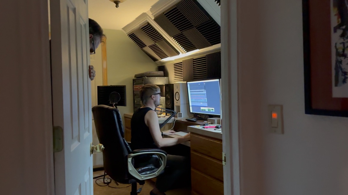 Brian at the editing desk: Pro Tools session open, acoustic treatment overhead, studio monitors