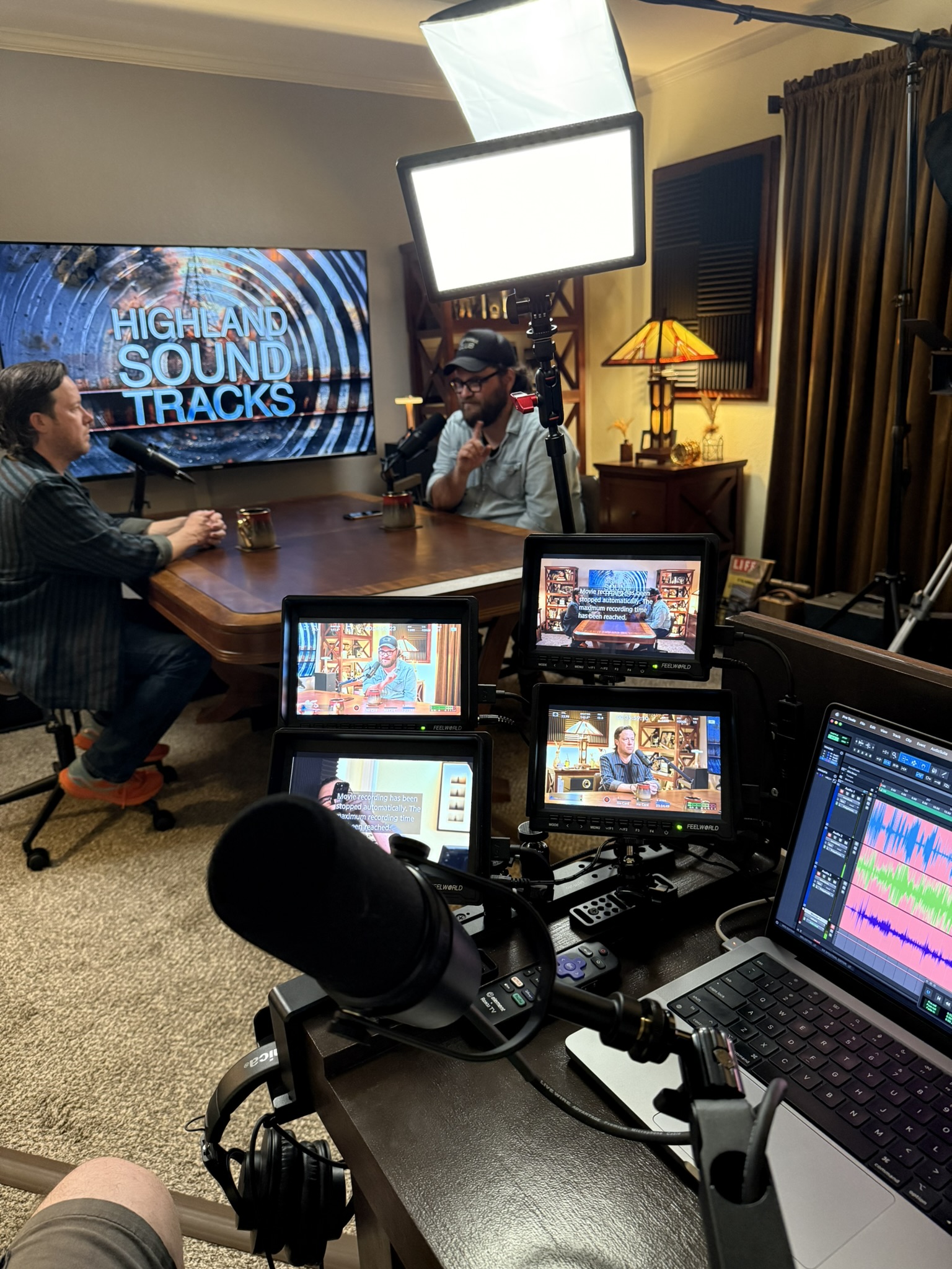 Travis at the director station: 4 camera monitors, Pro Tools, Highland Sound Tracks logo on the TV