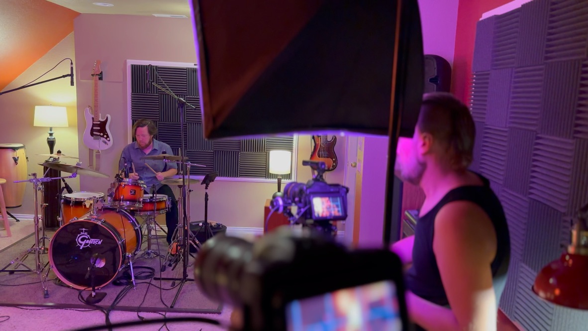 Travis operating camera while drummer plays on Gretsch kit, softbox lighting, acoustic panels